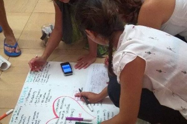 Educatrice scrive su un cartellone insieme a due bambine